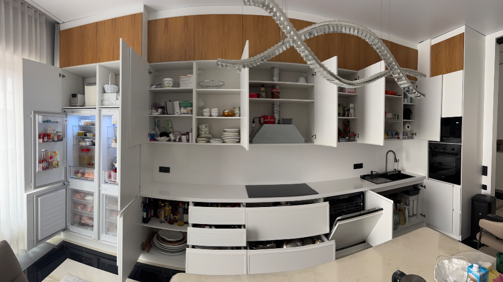 Кухня с открытыми дверцами шкафов, видна встроенная техника и продукты в холодильнике