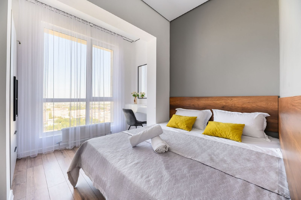 Уютная спальня с двуспальной кроватью и большим окном