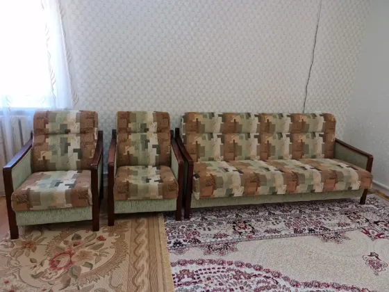 Диван и кресла в стиле ретро на ковре, уютная комната с окном