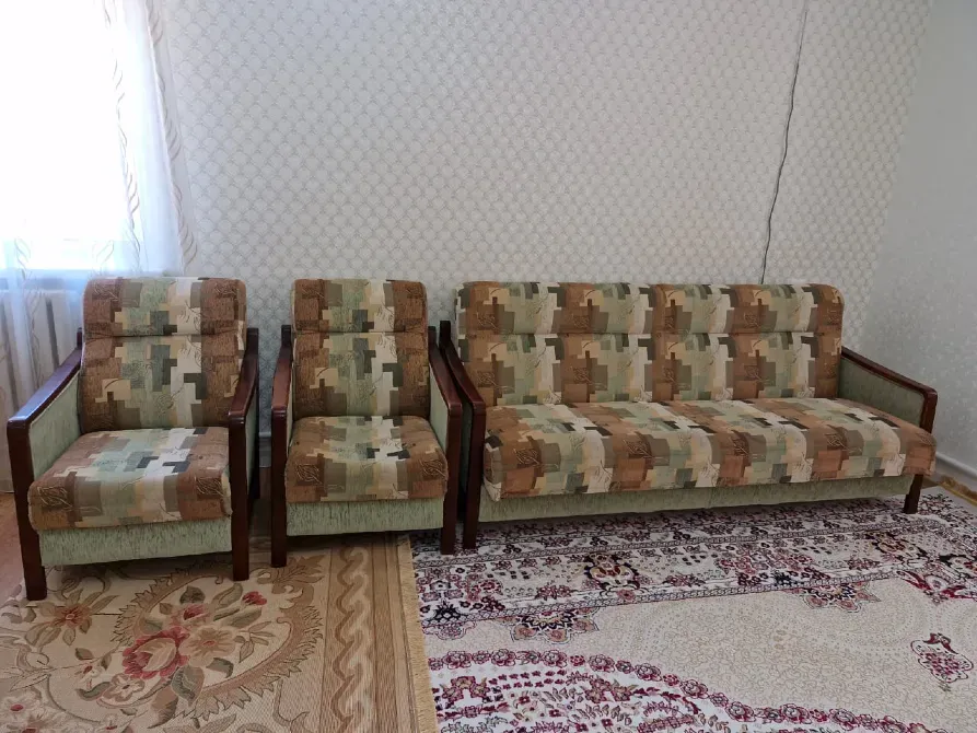 Диван и кресла в стиле ретро на ковре, уютная комната с окном