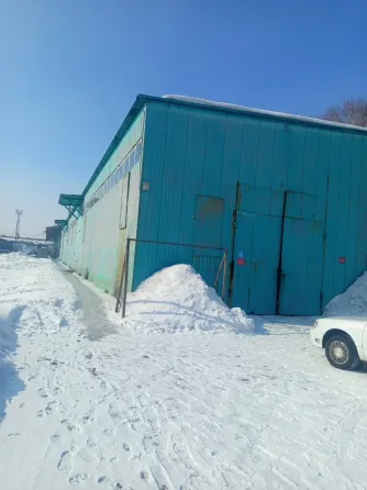 Здание холодного цвета на фоне зимнего пейзажа с кучами снега