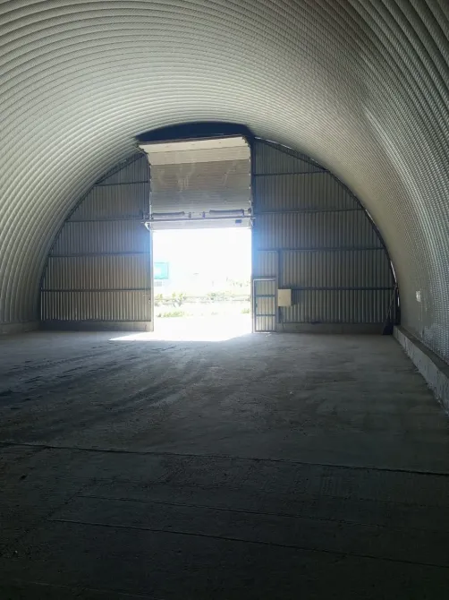 Интерьер ангарного помещения с открытыми воротами, вид на улицу