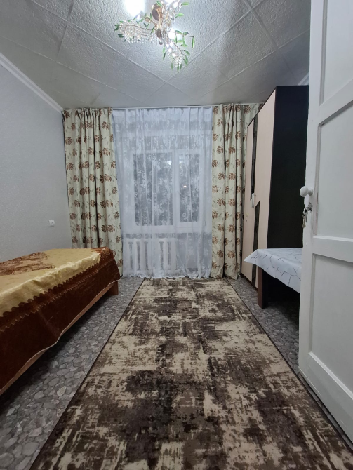 Помещение с двумя кроватями, ковром и окнами с занавесками