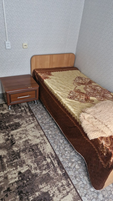 Уголок с одной кроватью, тумбочкой и ковром