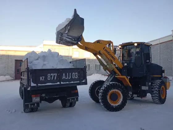 Погрузчик Liugong загружает снег в кузов грузовика на снежной площадке