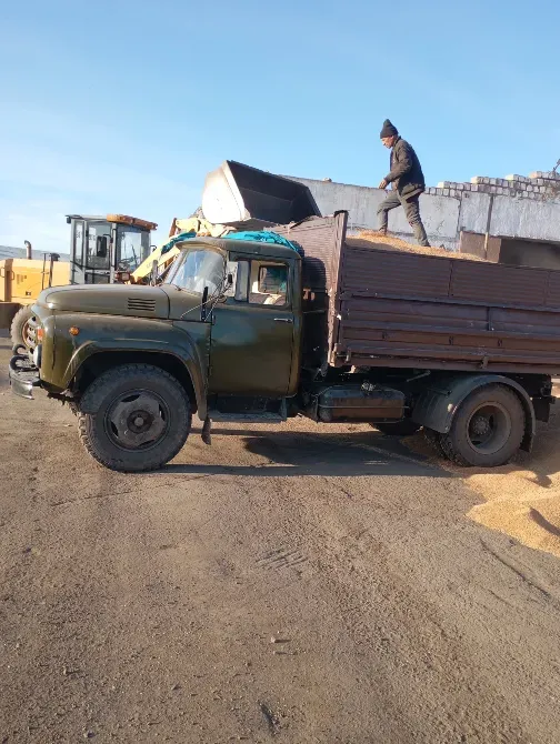 Грузовик на строительной площадке с рабочим, загружающим материал сверху