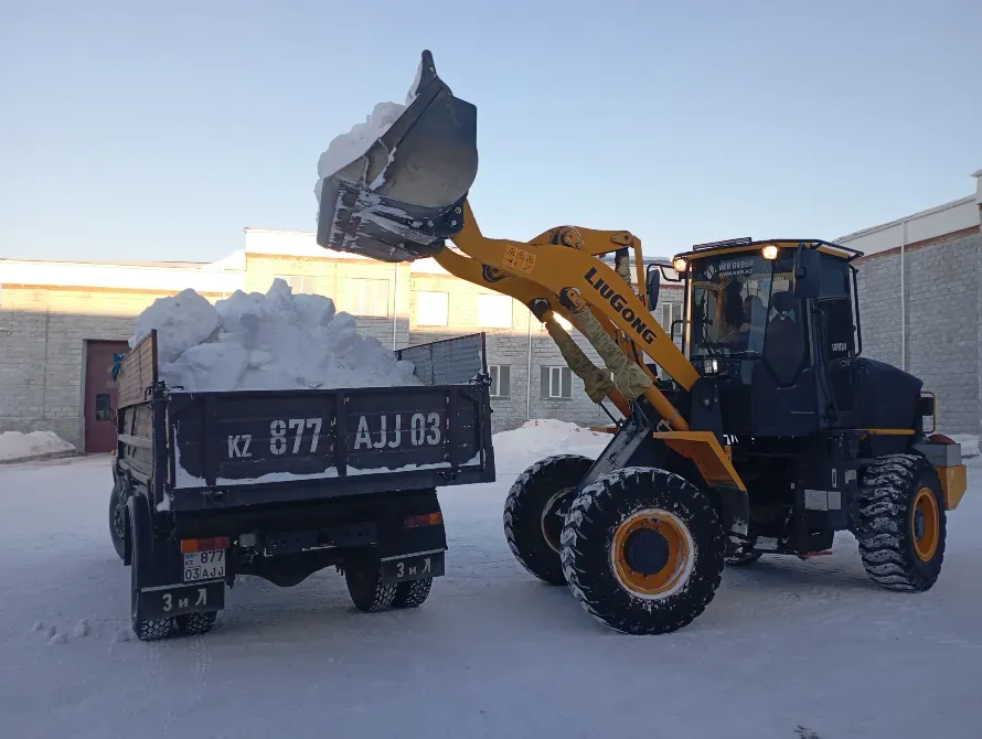 Погрузчик Liugong загружает снег в кузов грузовика на снежной площадке