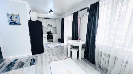 Современный интерьер комнаты с двуспальной кроватью, телевизором и обеденной зоной