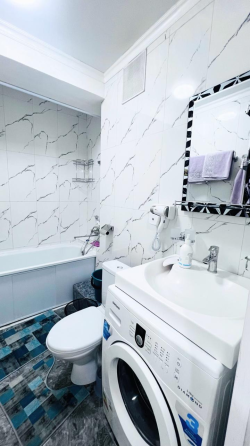 Современный интерьер комнаты с двуспальной кроватью, телевизором и обеденной зоной