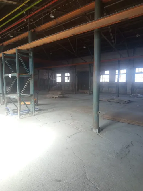 Пустое помещение склада с деревянными балками и длинными полками