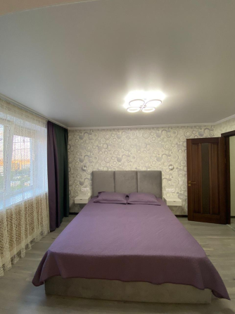 Современная спальня с кроватью и мягким текстилем на стенах