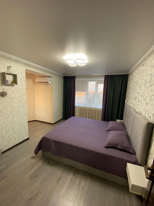 Современная спальня с кроватью и мягким текстилем на стенах