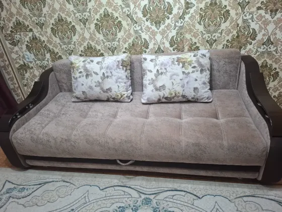 Диван с декоративными подушками на фоне обоев в классическом стиле