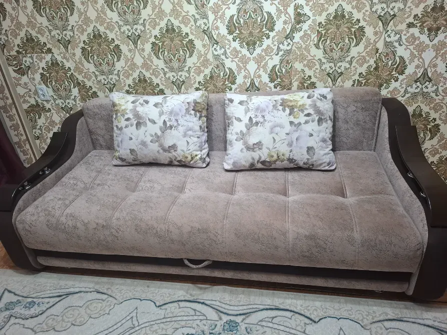 Диван с декоративными подушками на фоне обоев в классическом стиле