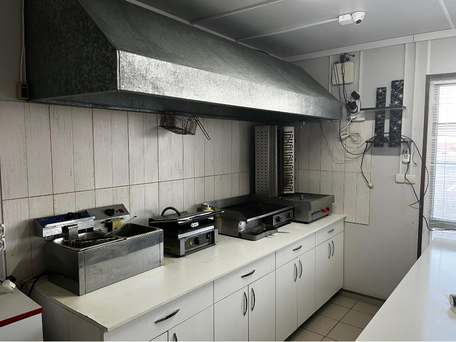кухня с оборудованием для готовки и вытяжкой