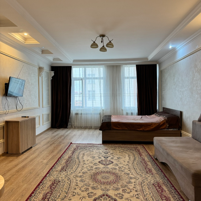 Спальня с двуспальной кроватью, телевизором и большими окнами