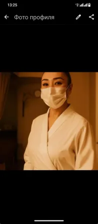 Женщина в халате и маске, стоящая в помещении с теплым светом