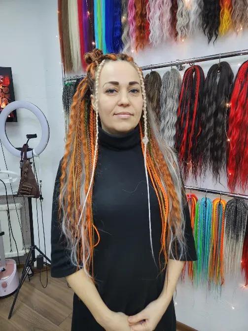 Женщина с яркими косами и аксессуарами, или с длинными прядями, на фоне салона