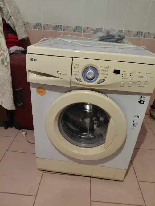 Стиральная машина LG в комнате с чемоданом и текстилем