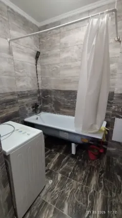 Спальня с одной двуспальной кроватью и диваном, оформленная в нейтральных тонах