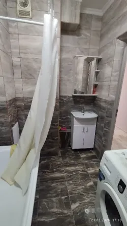 Спальня с одной двуспальной кроватью и диваном, оформленная в нейтральных тонах