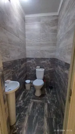 Спальня с одной двуспальной кроватью и диваном, оформленная в нейтральных тонах