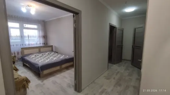 Спальня с одной двуспальной кроватью и диваном, оформленная в нейтральных тонах