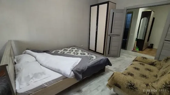 Спальня с одной двуспальной кроватью и диваном, оформленная в нейтральных тонах