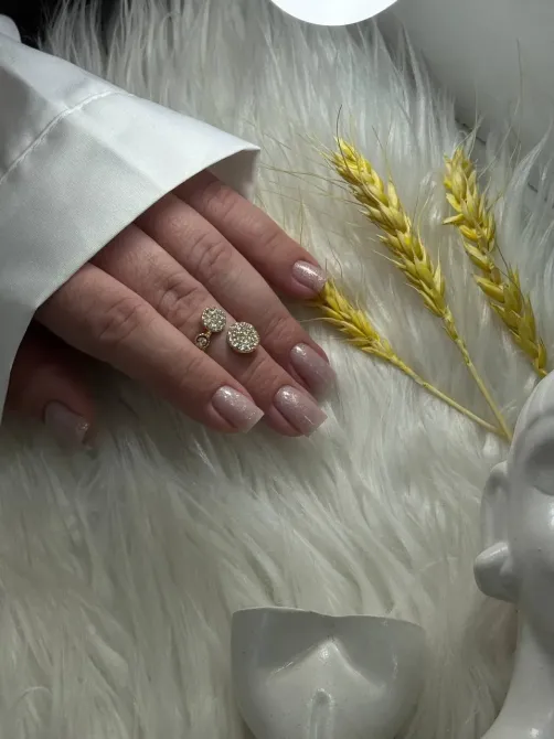 Изображение руки с аккуратным маникюром и кольцами на фоне светлой ткани