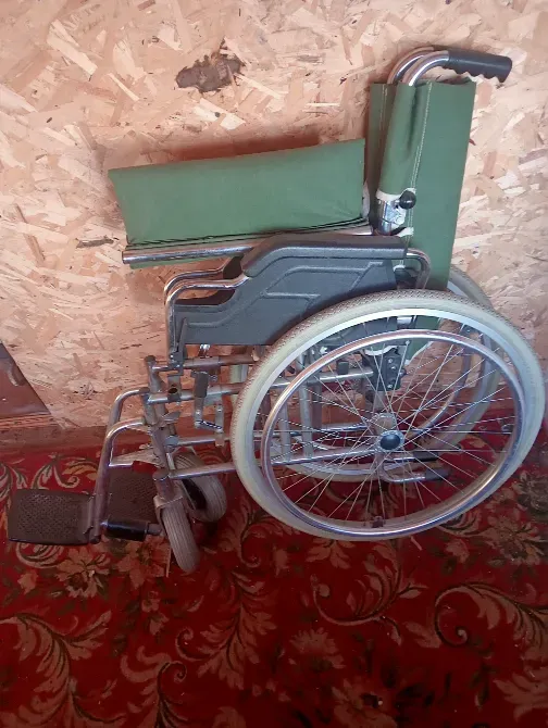 Инвалидная коляска с зелёной обивкой на ковровом покрытии