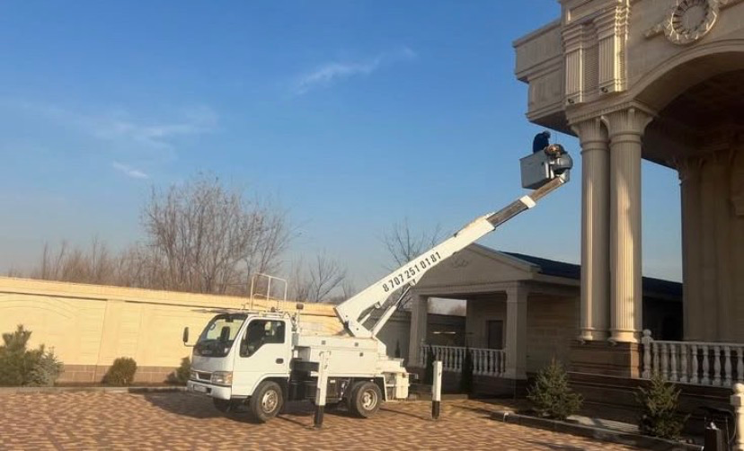 Грузовой автомобиль с подъемной установкой, работающий у здания