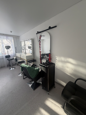 Интерьер парикмахерской с зеркалом и креслом, украшенным зеленым пледом