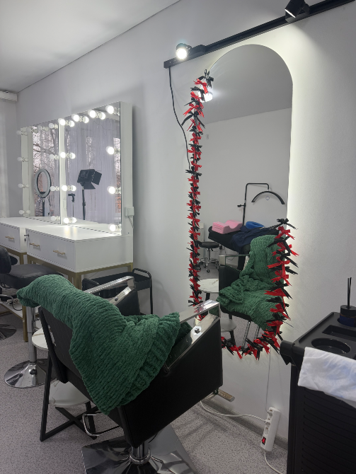 Интерьер парикмахерской с зеркалом и креслом, украшенным зеленым пледом