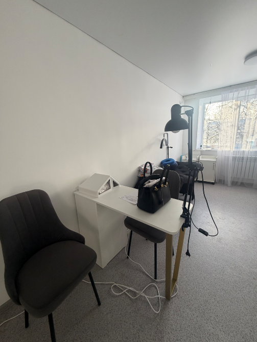 Оформление зоны отдыха с двумя стульями у белого стола в парикмахерской