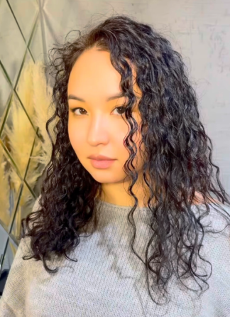 Женщина с кудрявыми волосами, смотрящая в камеру