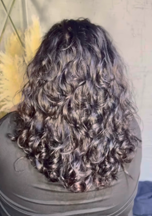 Женщина с кудрявыми волосами, смотрящая в камеру