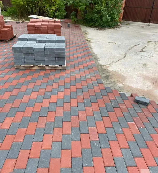 Стопка тротуарной плитки для мощения в красных и серых тонах на площадке