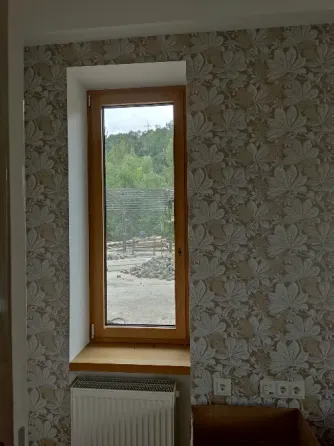 Окно с деревянной рамой в интерьере с цветной обоями и радиатором