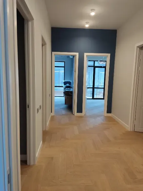 Коридор с дверями и стенами в светлых тонах, с выходом в другую комнату