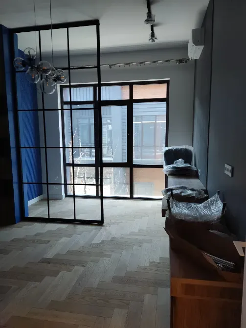 Современное помещение с большими окнами, перегородкой и стильной мебелью