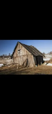 Ескі ағаш үй, ашық аспан фонында, ішінара қармен жабылған