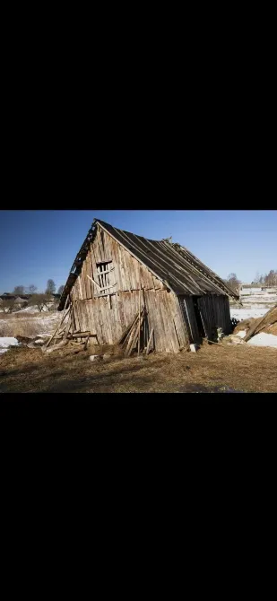 Старая деревянная хижина на фоне ясного неба, частично покрытая снегом