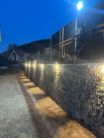 Светящаяся стена из габионов на фоне ночного неба