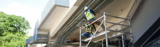 Рабочий на строительных лесах устанавливает электрооборудование