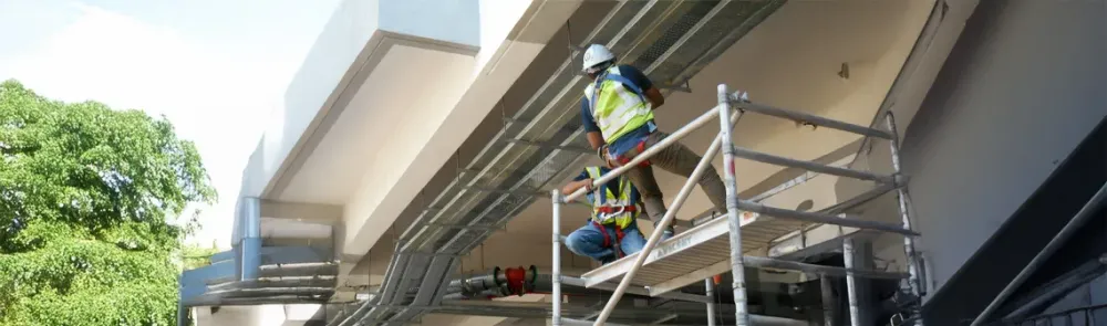 Рабочий на строительных лесах устанавливает электрооборудование