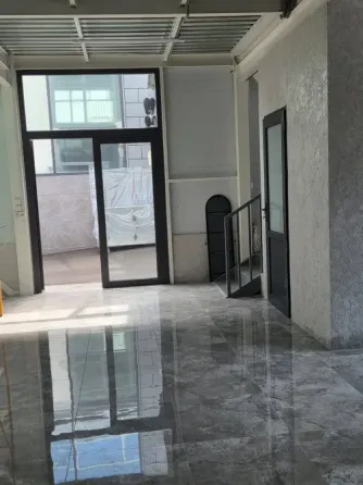 Современное коммерческое помещение с большими окнами, зеркальным полом и стеклянными дверями, придающими пространству светлый и просторный вид