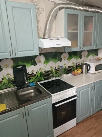 Кухня с голубыми шкафчиками, плитой и раковиной, оформленная обоями с изображением орхидей