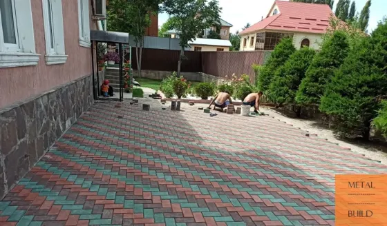 Работы по укладке плитки на улице с людьми, укладывающими плитку