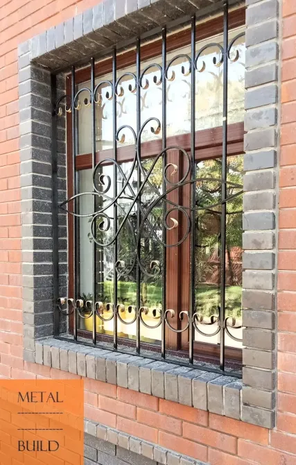 Металлическая решетка на окне кирпичного здания, украшенная узорами, обеспечивает безопасность и эстетический вид