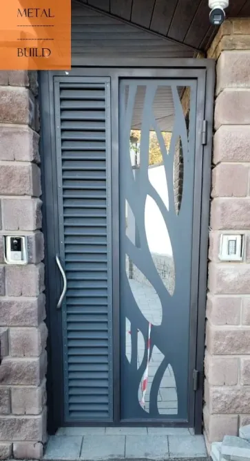 Элегантная металлическая дверь с ажурным стеклом и декоративными элементами, установленная в каменном проеме